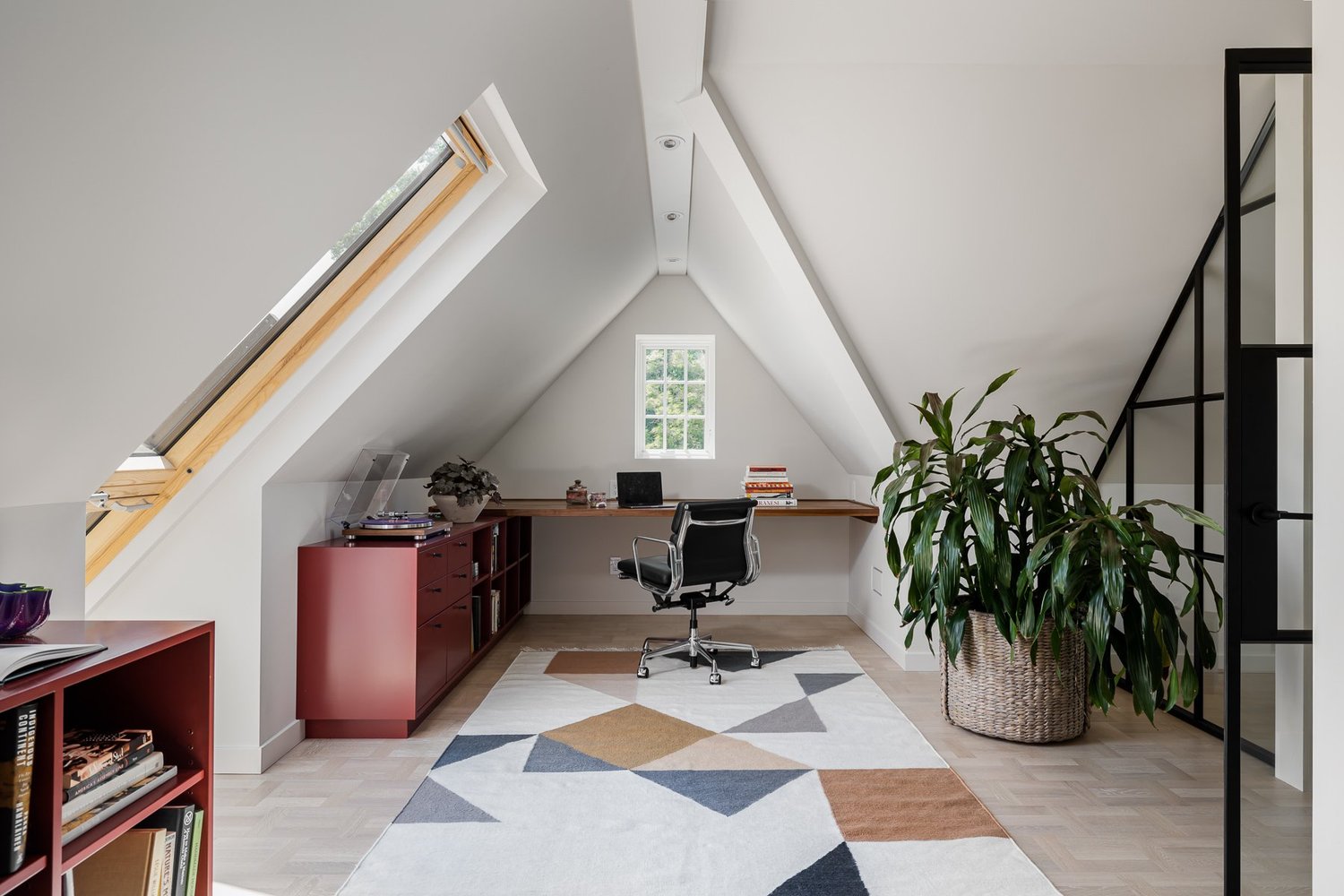 Home office with slanted ceiling and large greenery