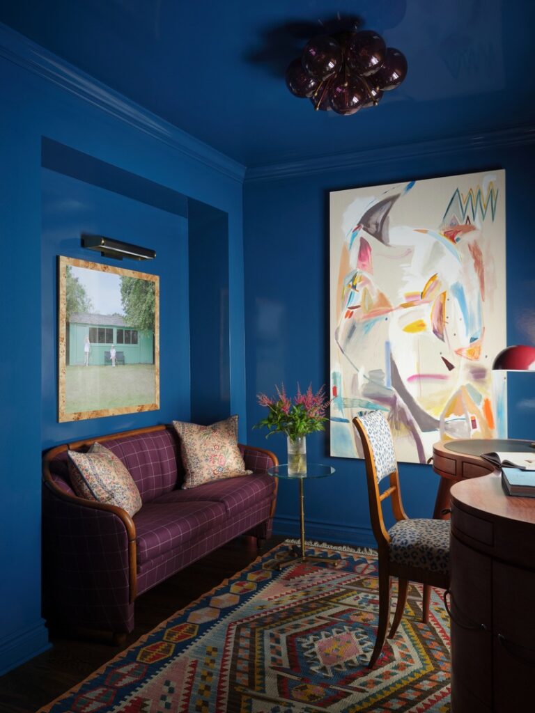 Blue painted walls with art work and mauve colored couch