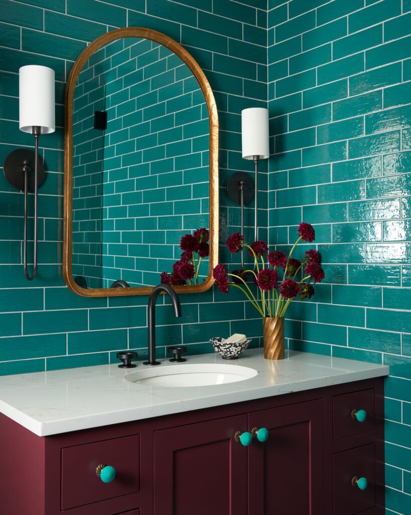 teal wall tile and oxblood vanity in a powder bath
