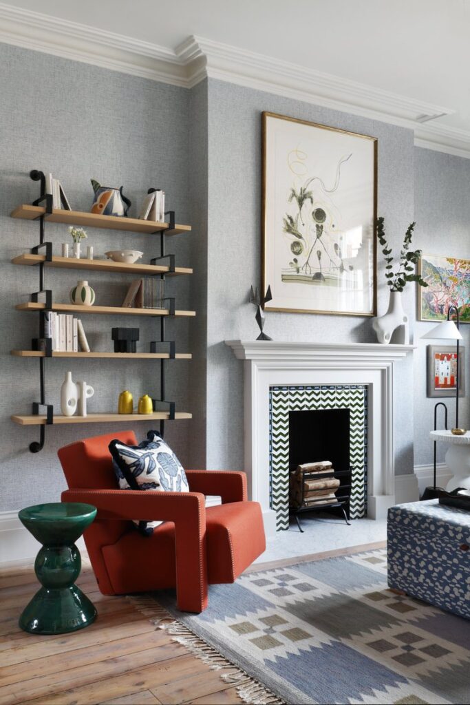 sitting room with red chair and layered shelves and fireplace