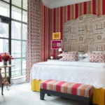 A brightly striped wallpapered guest room at The Whitby Hotel in New York City