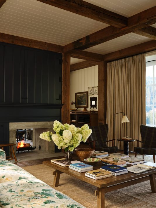 Dark beams in living room with layered books on coffee table