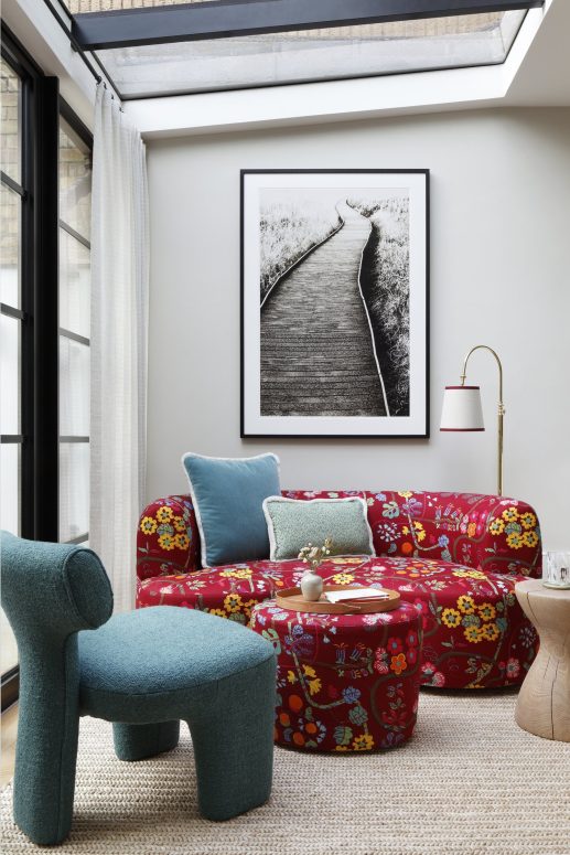 red floral couch with teal pillows and additional chair