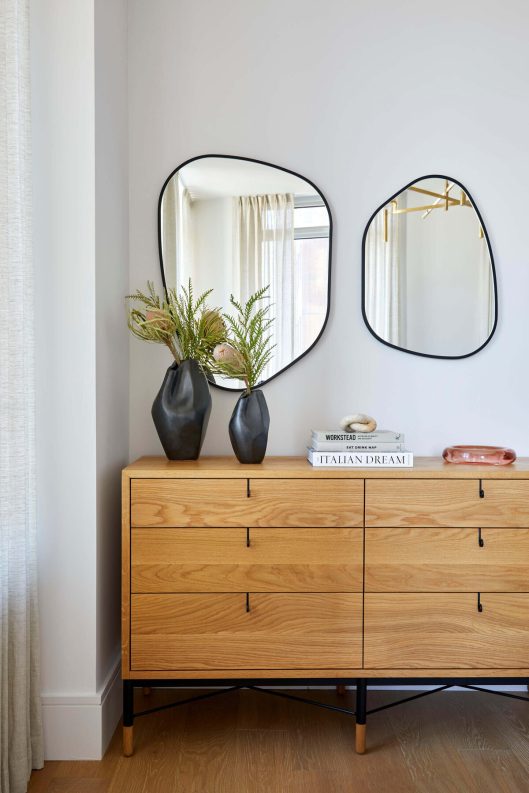 Two circular mirrors over a dresser