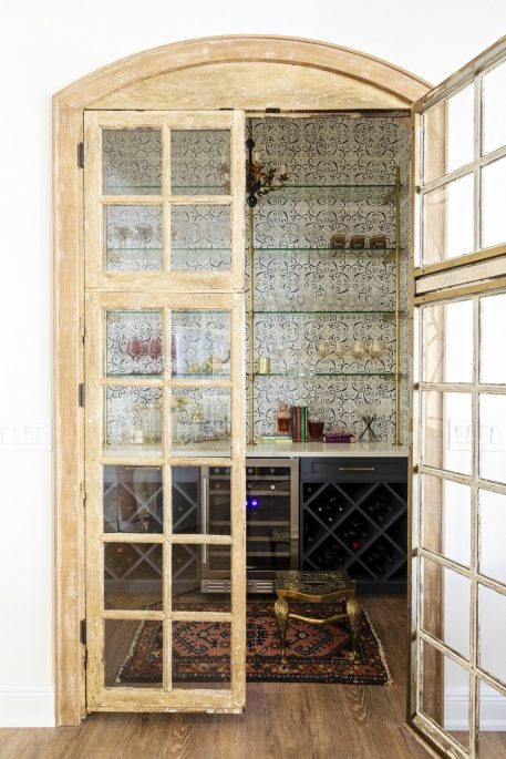 Modern bar setup tucked away behind vintage French doors