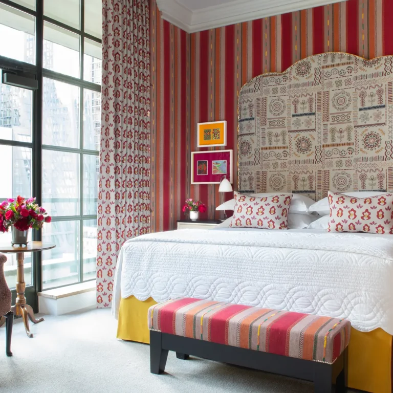 A brightly striped wallpapered guest room at The Whitby Hotel in New York City